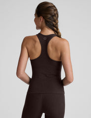 woman wearing a brown racerback and full length tank top and leggings on a plain background.