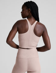 model wearing a beige high neck racerback cropped tank top and beige high-waisted midi length leggings against a plain background.