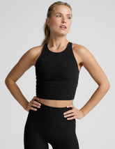 woman wearing a black high neck racerback cropped tank on a plain background.