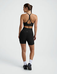 woman wearing a black sports bra and pocket biker shorts shorts on a plain background.