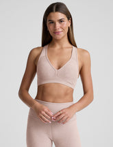 model wearing a pink v-neck sports bra and leggings on a plain background.