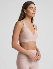 model wearing a pink v-neck sports bra and leggings on a plain background.