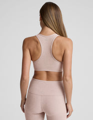 model wearing a pink v-neck sports bra and leggings on a plain background.