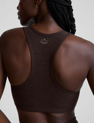 woman wearing a brown v-neck sports bra and pants on a plain background.