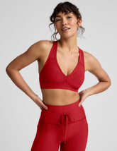 Woman wearing a red v-neck bra and leggings on a light background.