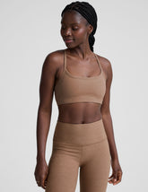 model wearing a brown slim strapped racerback bra and leggings on a light gray background.
