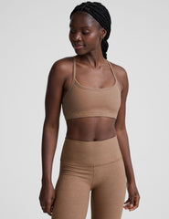 model wearing a brown slim strapped racerback bra and leggings on a light gray background.