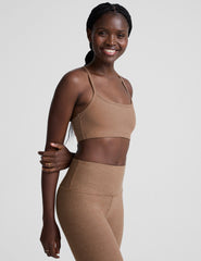 model wearing a brown slim strapped racerback bra and leggings on a light gray background.