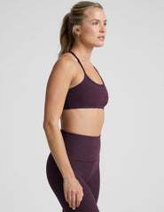 model wearing a purple slim strapped racerback bra and leggings on a light gray background.