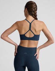 person wearing a blue slim racerback bra with leggings against a plain background.