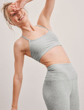 model is wearing a gray racerback bra with slim spaghetti straps.