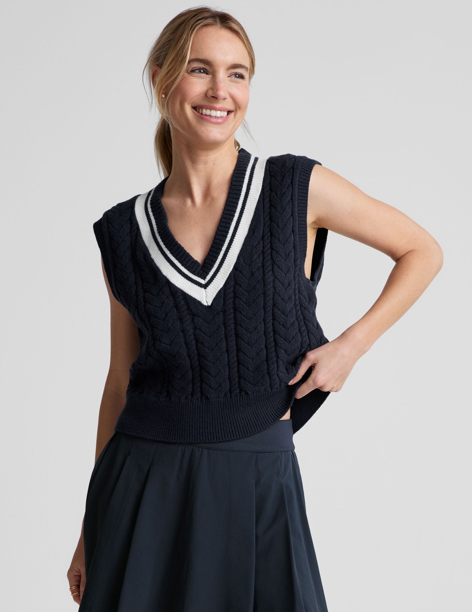 blue relaxed fit cable knit sweater vest with a v neckline with contrast color stripe.