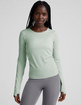model wearing a light green long-sleeve crewneck top and gray leggings on a plain background.