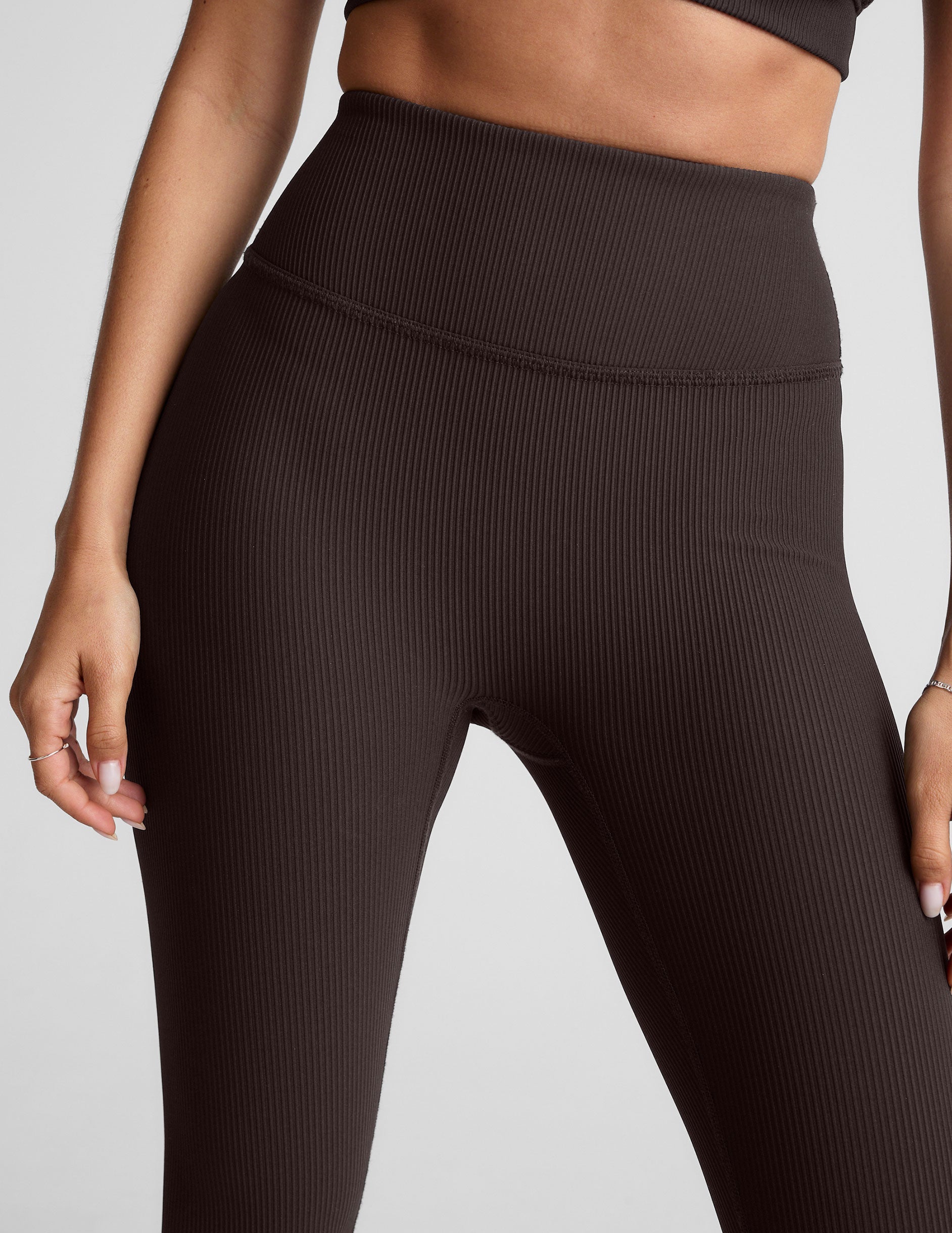 model wearing brown ribbed high-waisted midi length leggings against a plain background.