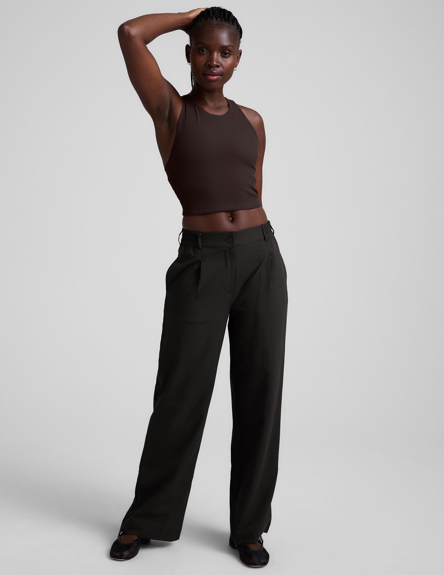 model is wearing a brown ribbed high-neck racerback cropped tank against a plain background.