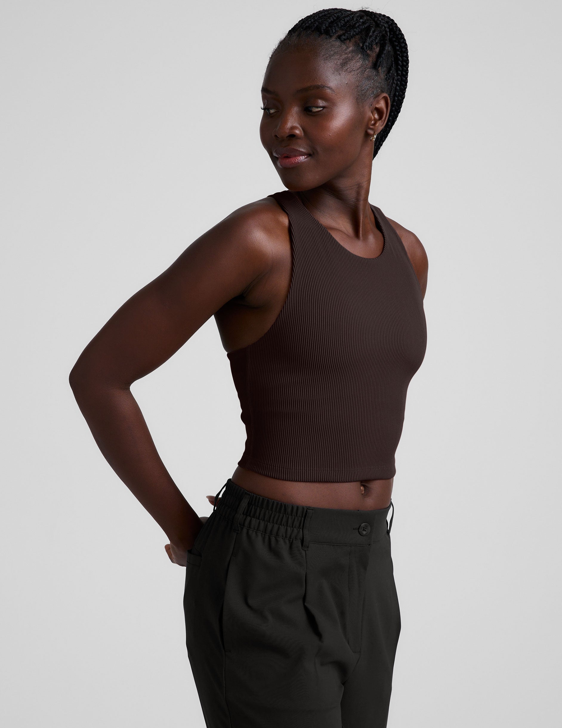 model is wearing a brown ribbed high-neck racerback cropped tank against a plain background.