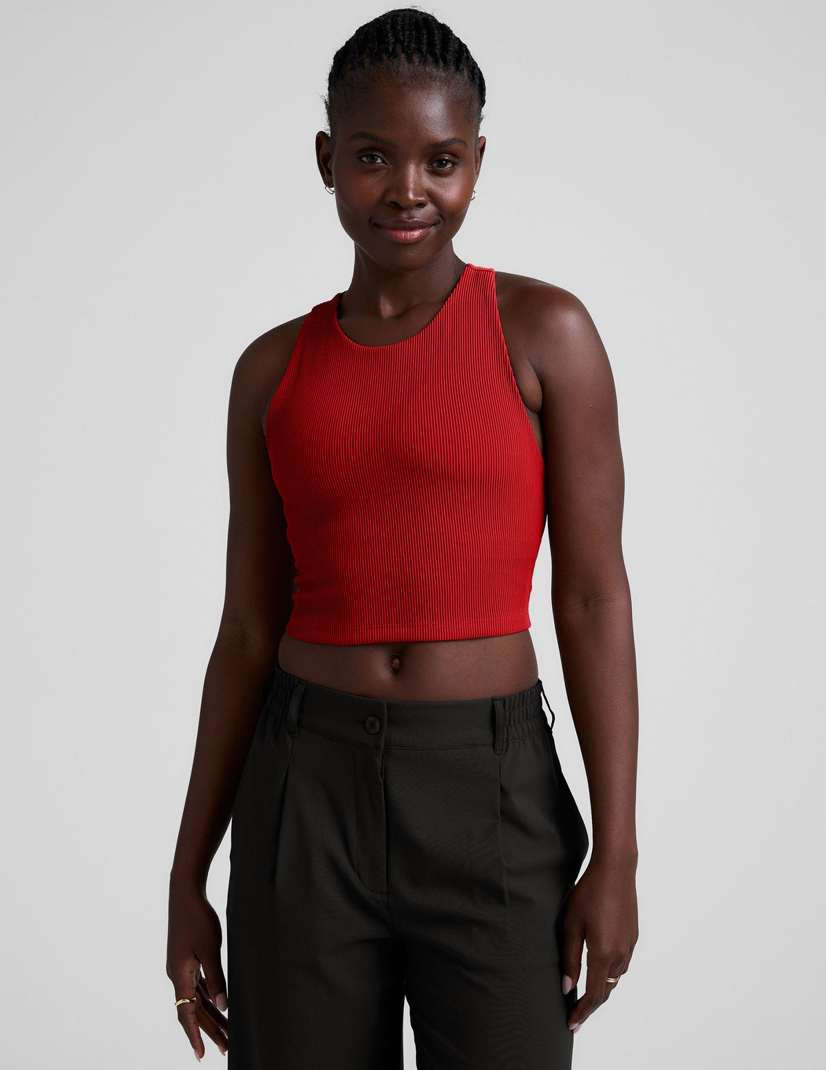 model is wearing a red ribbed high-neck racerback cropped tank top against a plain background.