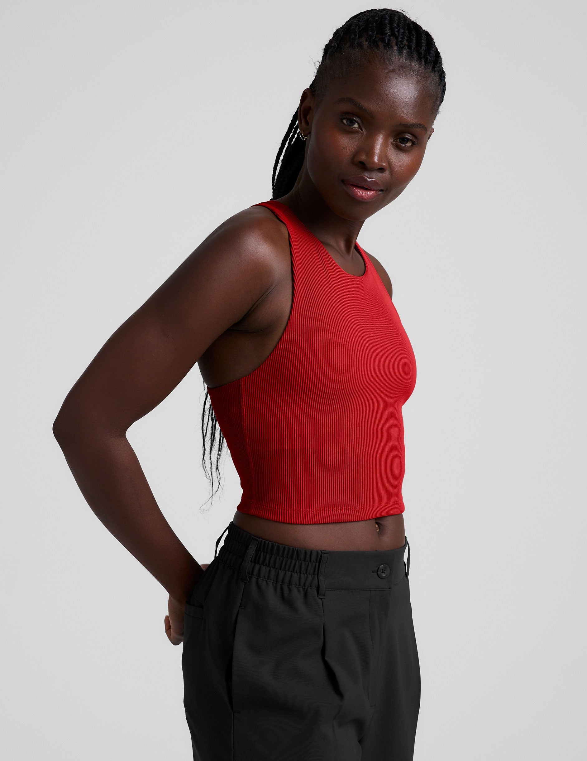 model is wearing a red ribbed high-neck racerback cropped tank top against a plain background.