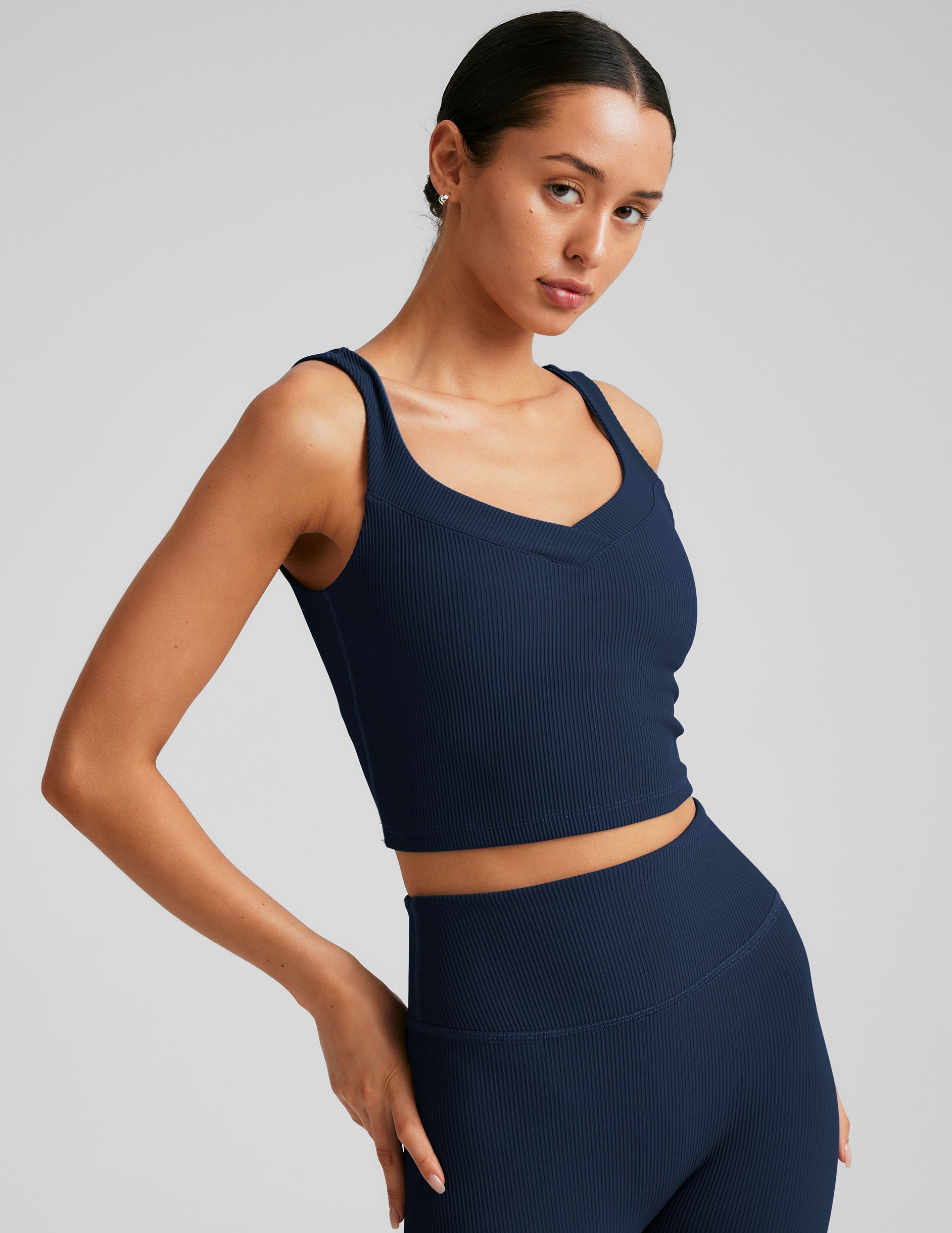 blue ribbed cropped tank top with a soft V neckline front and back​, an overlapping front neckline detail​, and a lining shelf bra​. 