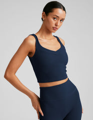 blue ribbed cropped tank top with a soft V neckline front and back​, an overlapping front neckline detail​, and a lining shelf bra​. 