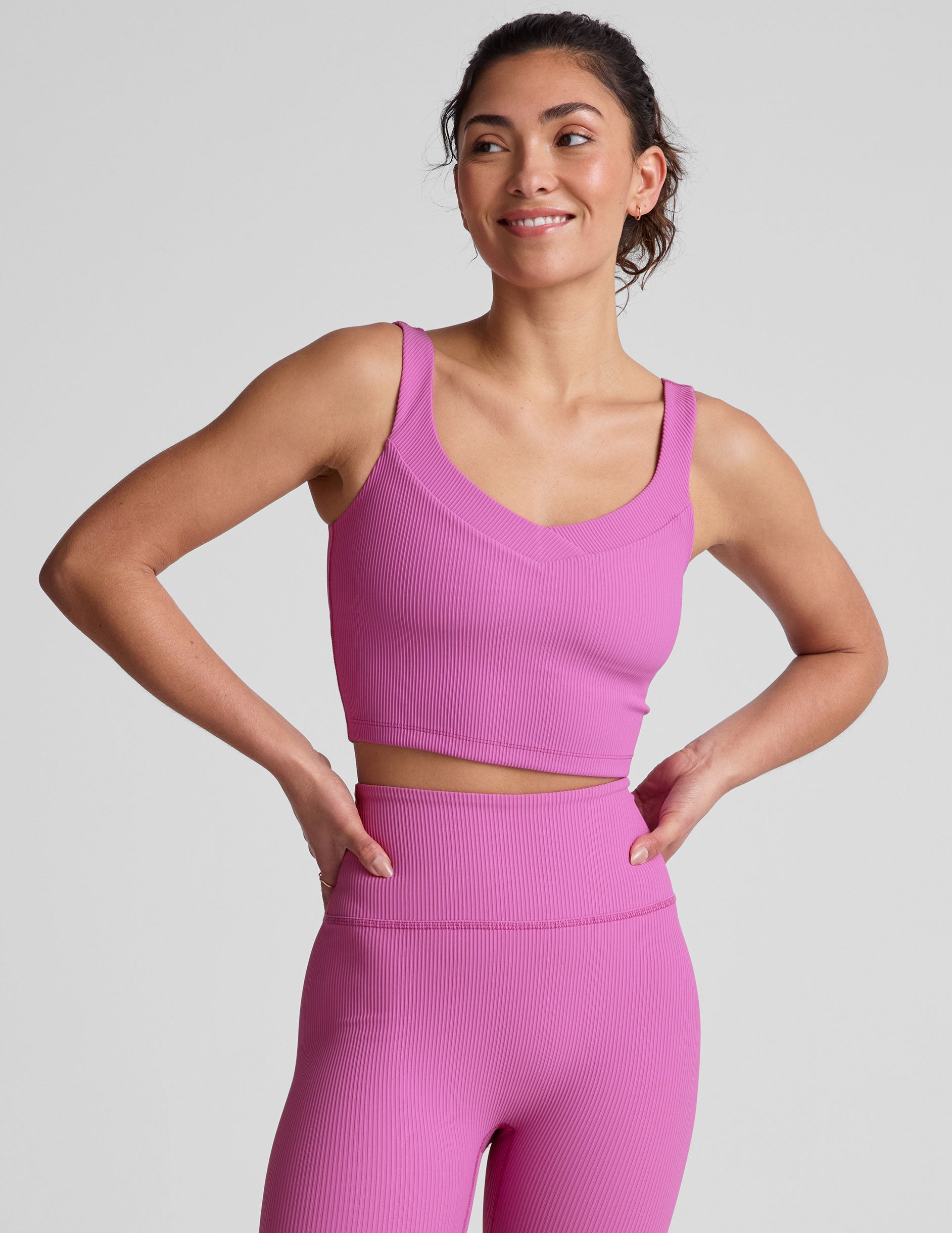 pink ribbed cropped tank top with a soft V neckline front and back​, an overlapping front neckline detail​, and a lining shelf bra​. 