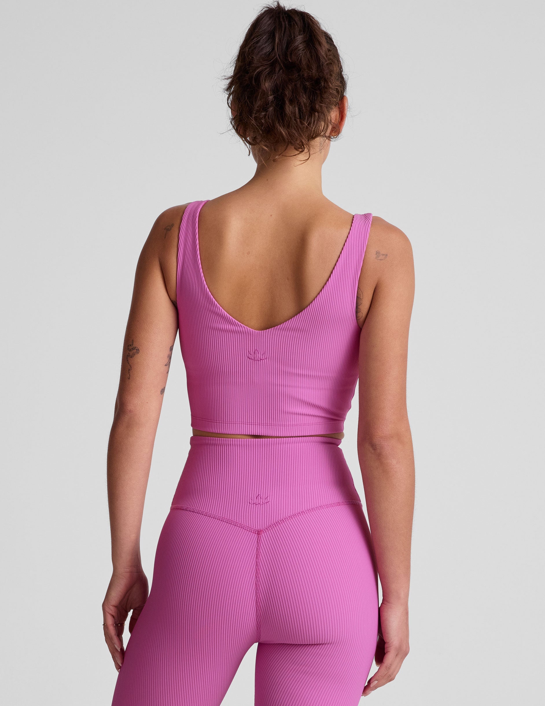 pink ribbed cropped tank top with a soft V neckline front and back​, an overlapping front neckline detail​, and a lining shelf bra​. 
