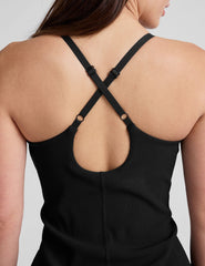 black ribbed mini length dress with a soft scoop front neckline​, back strap cross-over detail, overlapping front hem detail​, and interior shorts ​with pockets. 