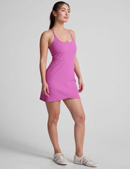 pink ribbed mini length dress with a soft scoop front neckline​, back strap cross-over detail, overlapping front hem detail​, and interior shorts ​with pockets. 