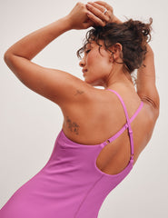 pink ribbed mini length dress with a soft scoop front neckline​, back strap cross-over detail, overlapping front hem detail​, and interior shorts ​with pockets. 