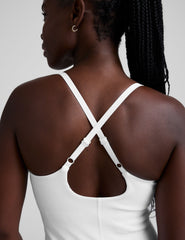 white ribbed mini length dress with a soft scoop front neckline​, back strap cross-over detail, overlapping front hem detail​, and interior shorts ​with pockets. 