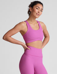 pink medium support racerback bra with a scoop neckline​, overlapping hemband detail​, is lined with performance lining and powermesh in between​, and has removable bra pads​. 