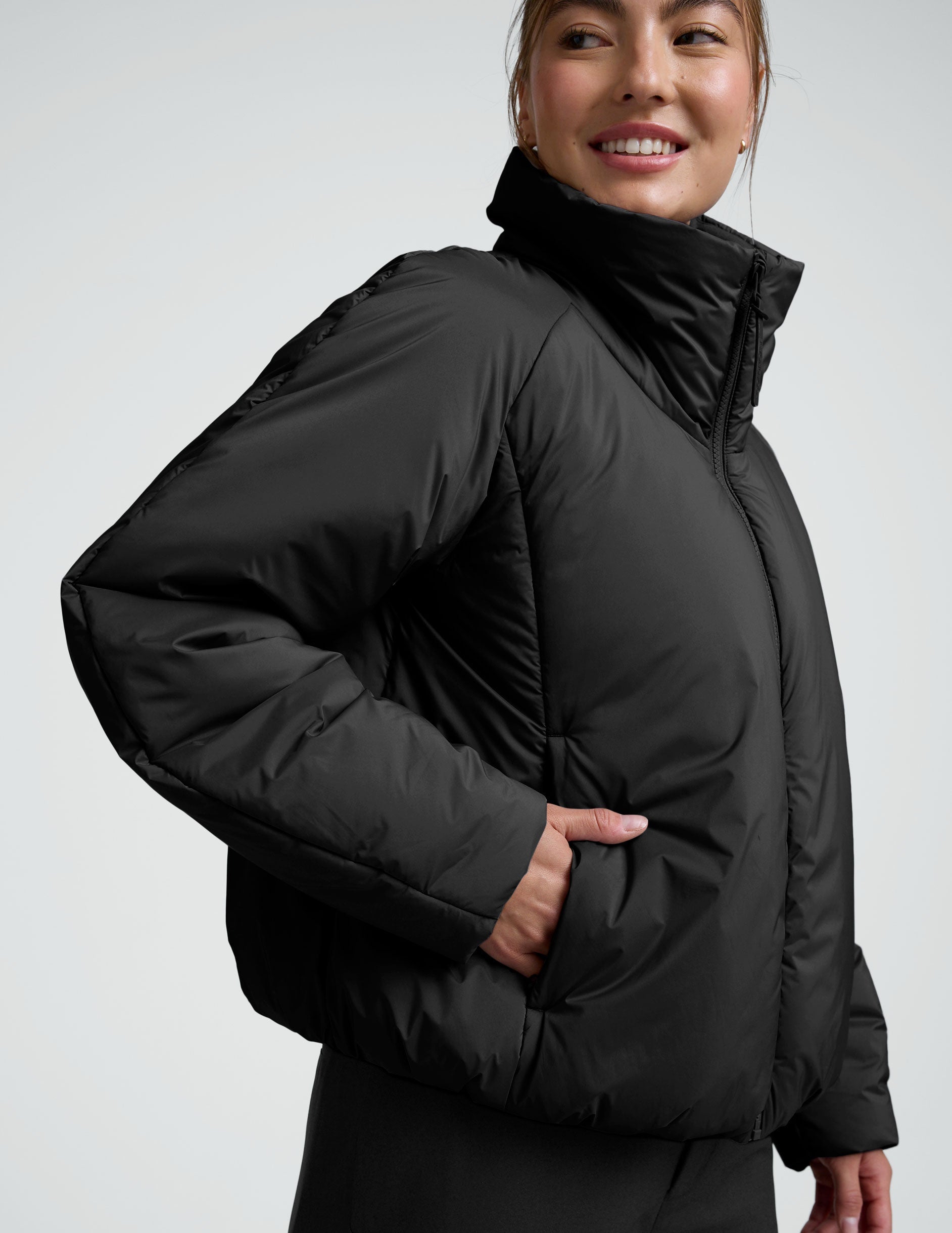 Person wearing a black zip-up puffer jacket and pants on a plain background.