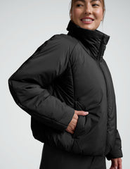 Person wearing a black zip-up puffer jacket and pants on a plain background.