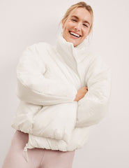 woman wearing a white puffer jacket against a light background.