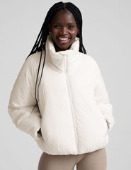 model wearing a white puffer jacket against a plain background.