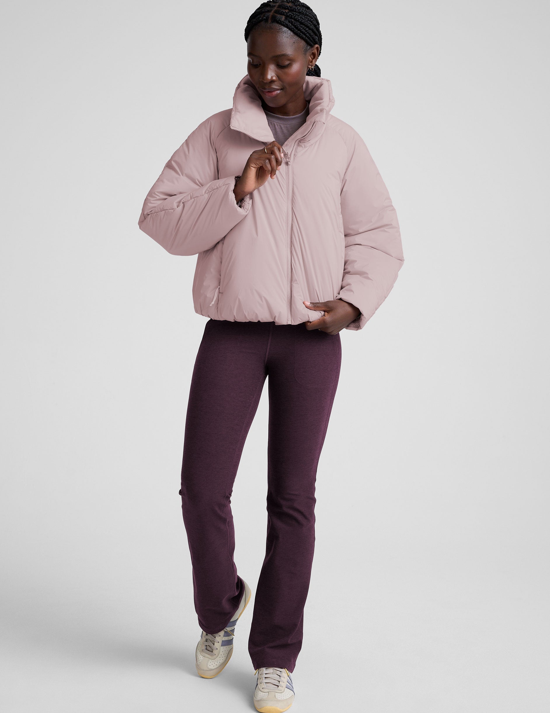 model wearing a light pink puffer jacket on a light background.