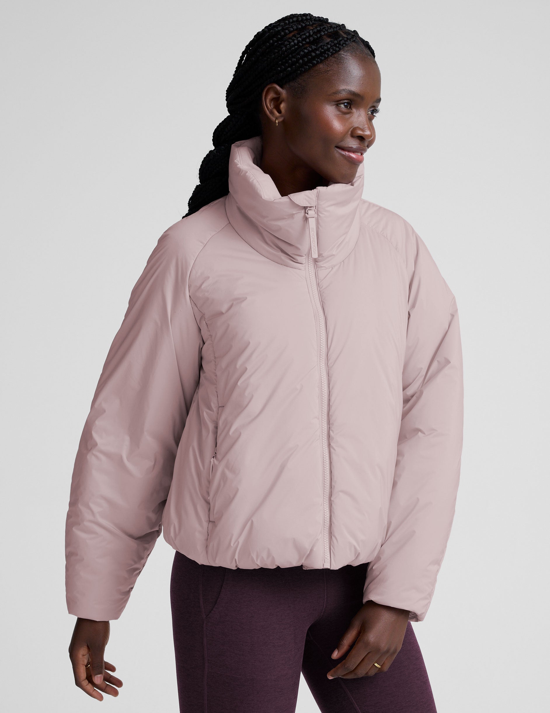 model wearing a light pink puffer jacket on a light background.