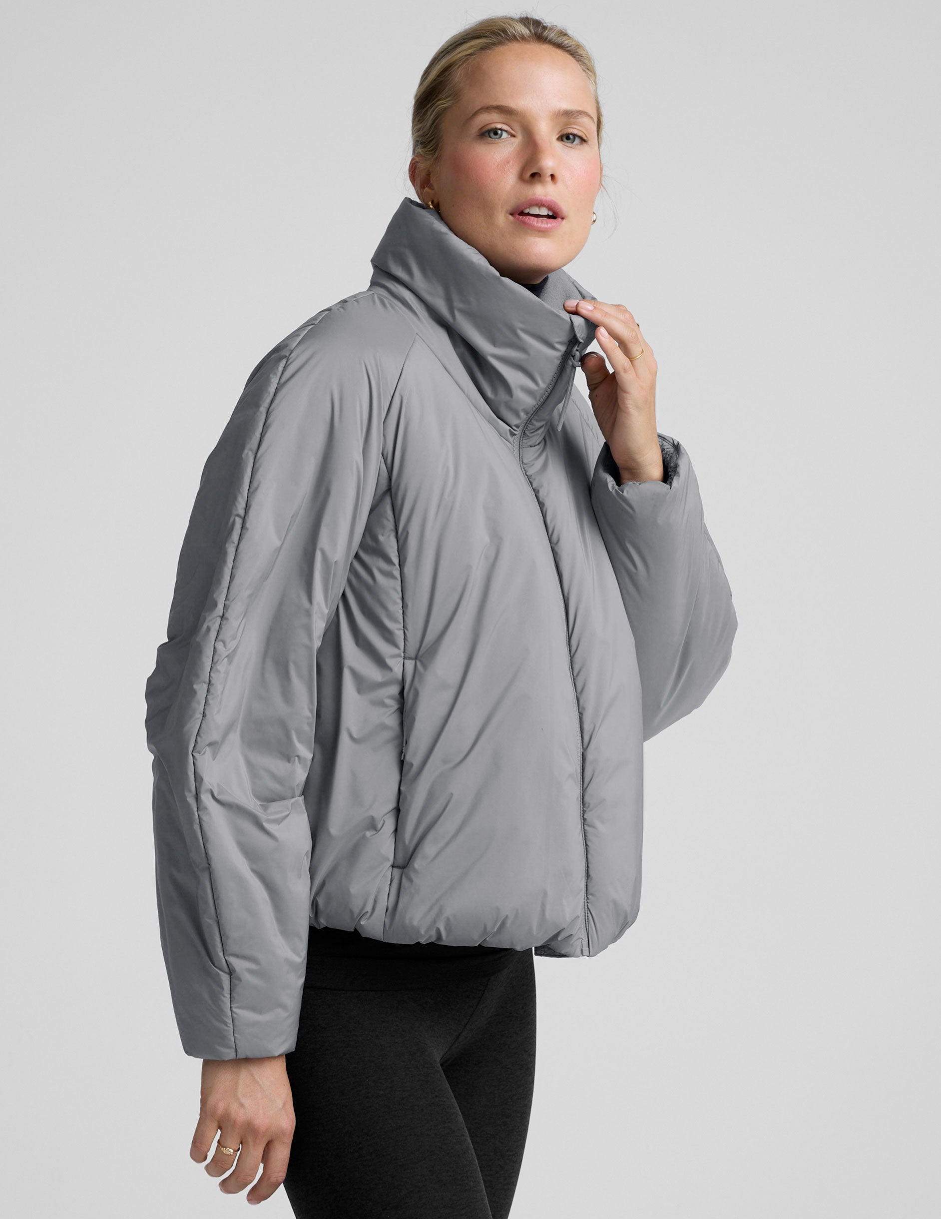 model wearing a gray puffer jacket on a light gray background.
