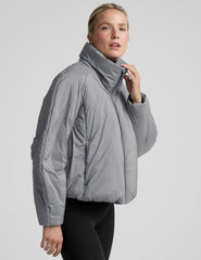 model wearing a gray puffer jacket on a light gray background.