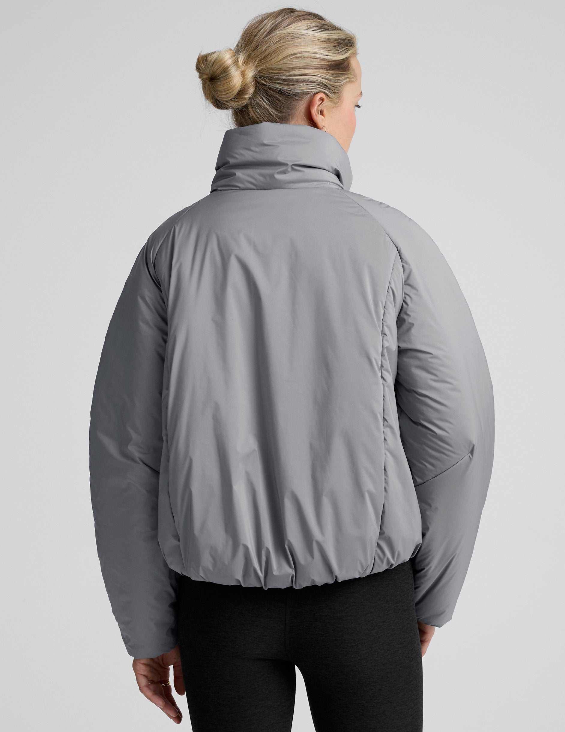 model wearing a gray puffer jacket on a light gray background.