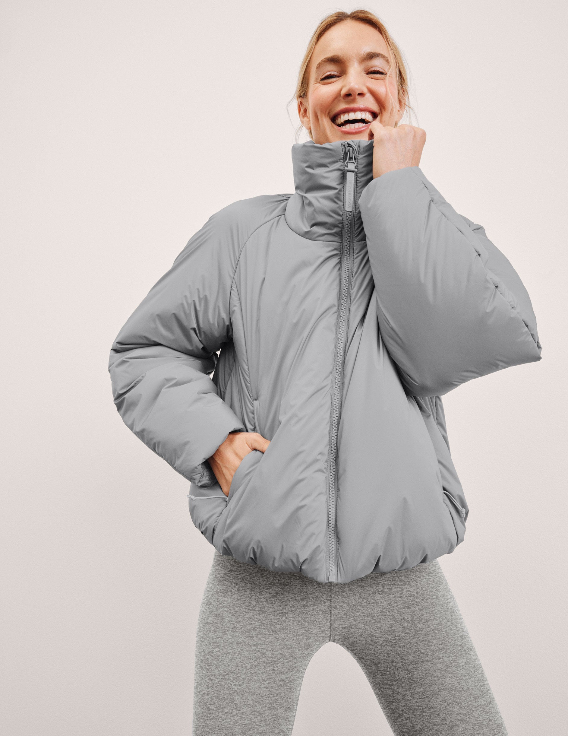 model wearing a gray puffer jacket on a light gray background.