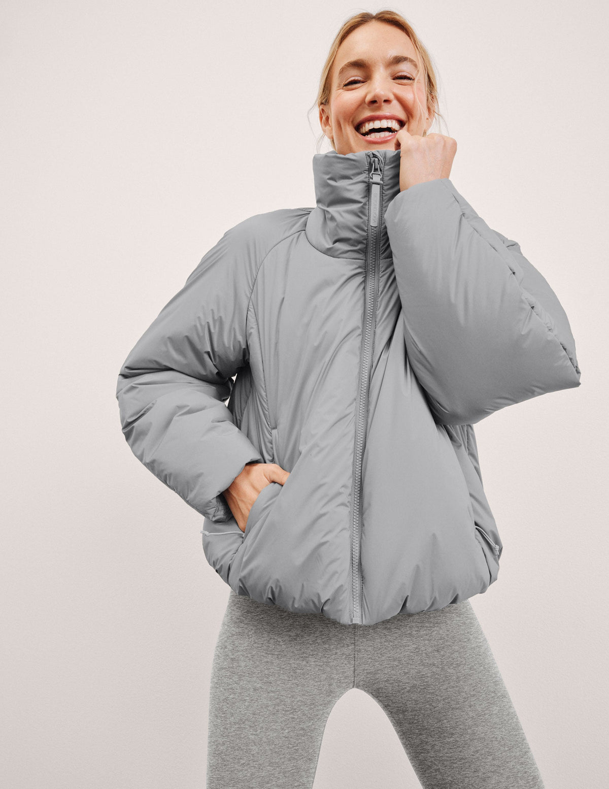 model wearing a gray puffer jacket on a light gray background.
