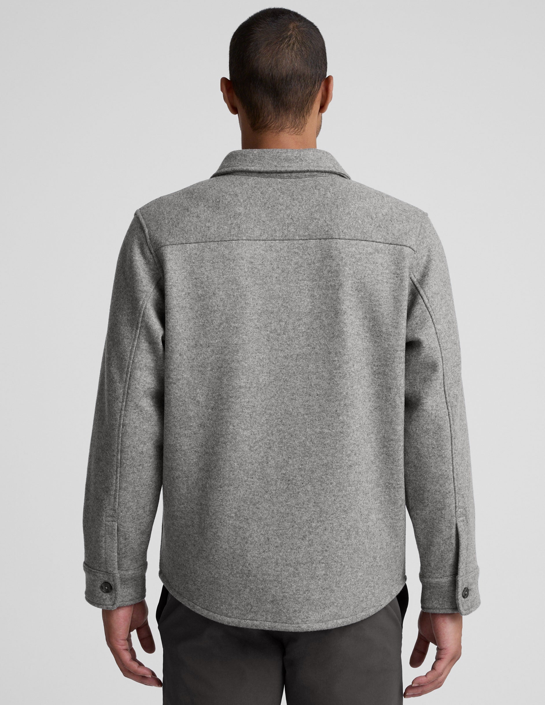 model wearing a gray men's button up jacket over a black shirt on a light gray background.