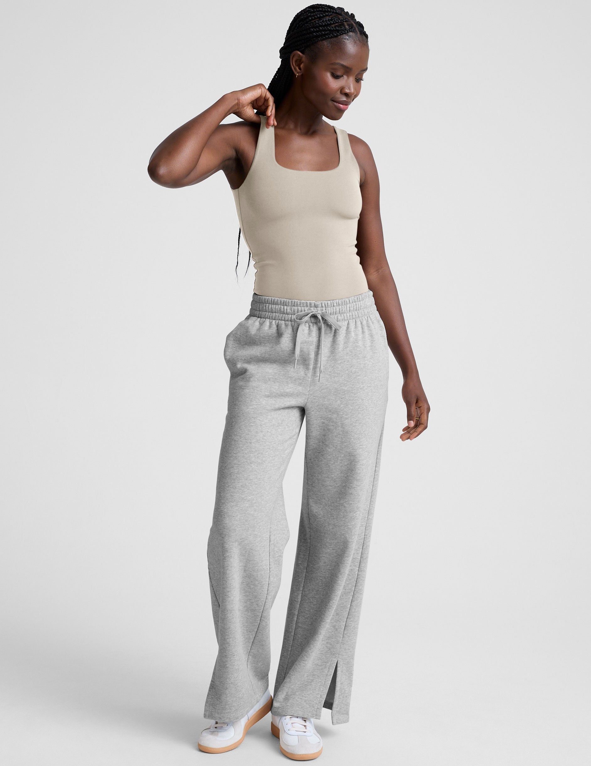 model wearing a beige square neck body suit and gray sweatpants against a plain background.