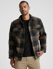 model wearing a men's plaid button-up jacket over a black shirt on a light gray background.