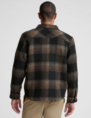 model wearing a men's plaid button-up jacket over a black shirt on a light gray background.