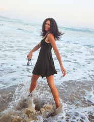 model is wearing a black square neck tank mini dress with pockets.