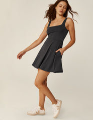 model is wearing a black square neck tank mini dress with pockets.