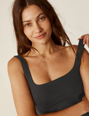 model is wearing a black square neck tank mini dress with pockets.