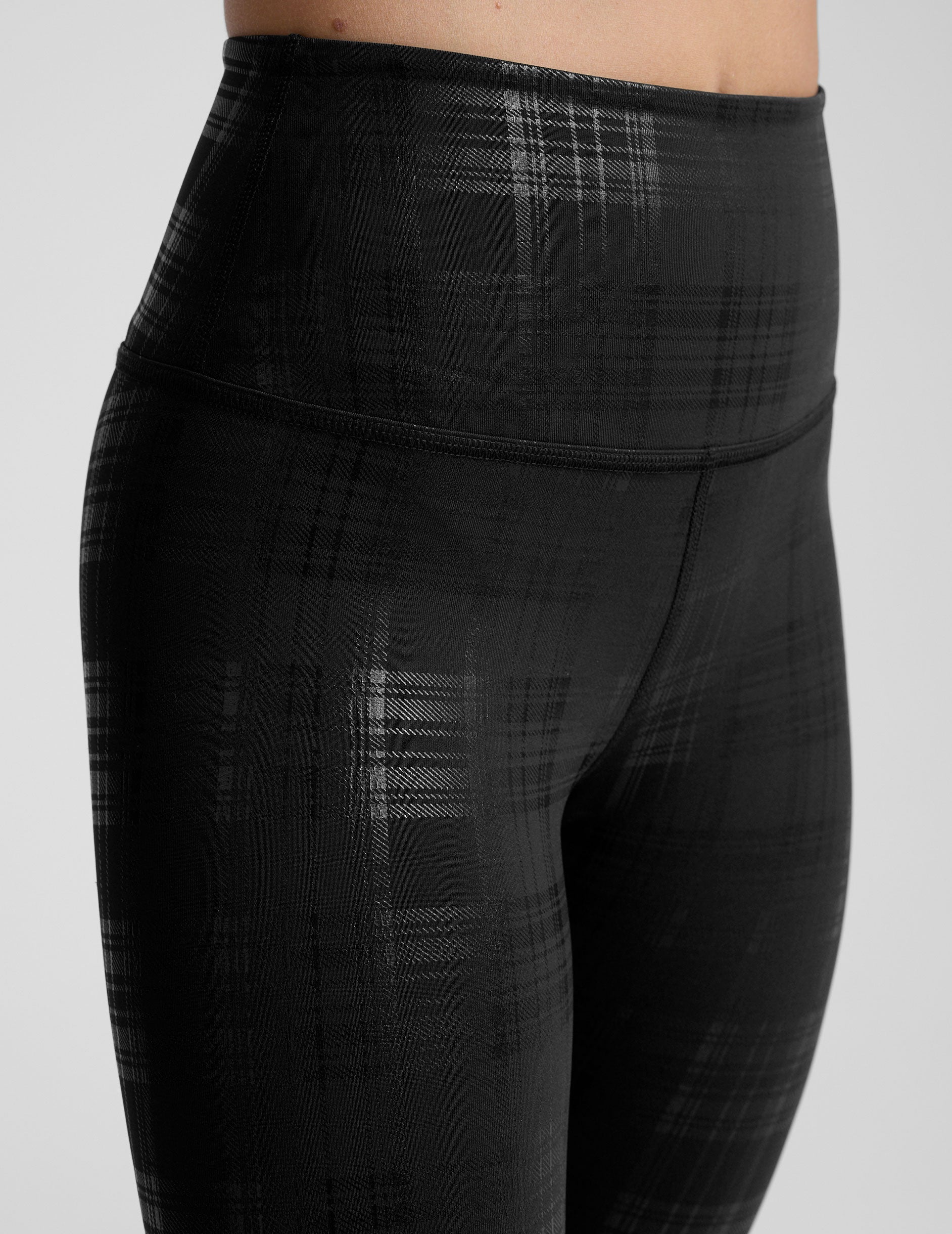 model wearing black plaid foil leggings on a white background.